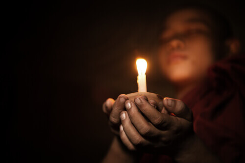 Niño budista con una vela meditando