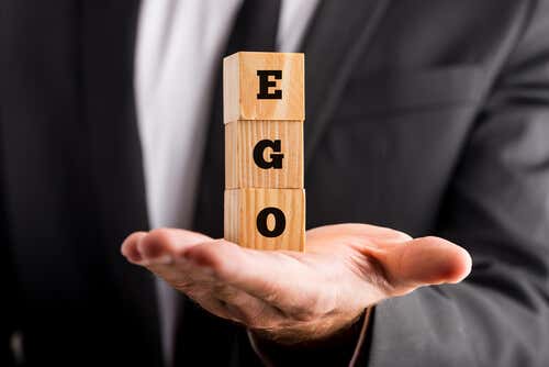 Hombre sosteniendo la palabra ego en unos cubos de madera