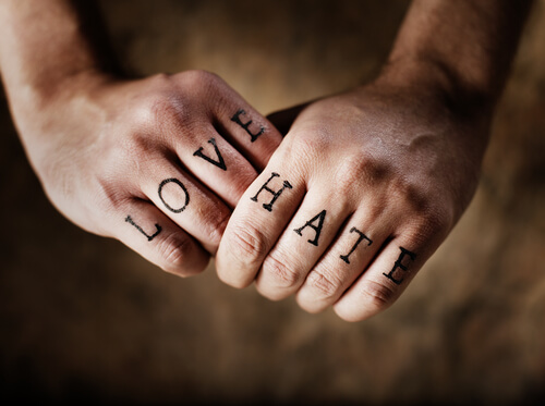 Manos con palabras amor y odio tatuadas