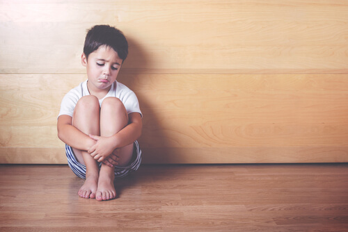 Niño triste sentado en un rincón