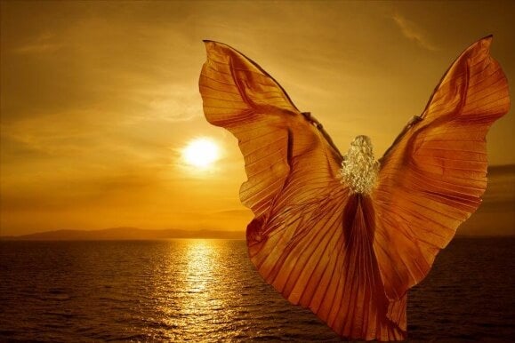 Mujer con alas soñando frente al mar