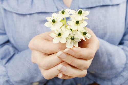 Mani che offrono fiori per aumentare la autostima.