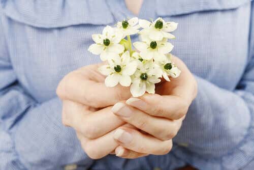 Mani che offrono fiori per aumentare la autostima.