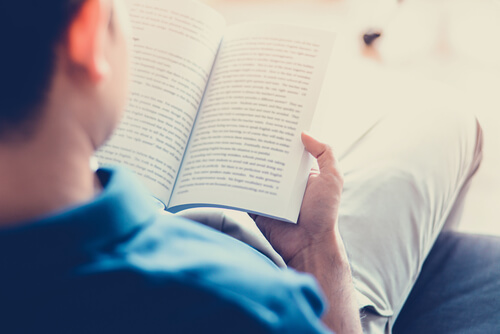 hombre leyendo libro en el sofá