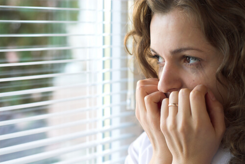 Mujer con miedo mirando por la ventana