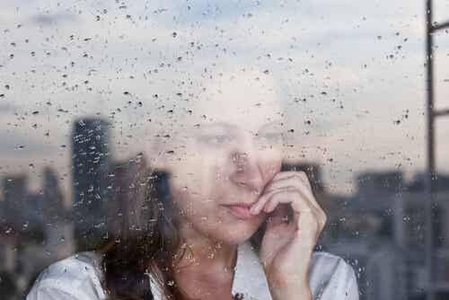 Mujer mirando por la ventana con lluvia