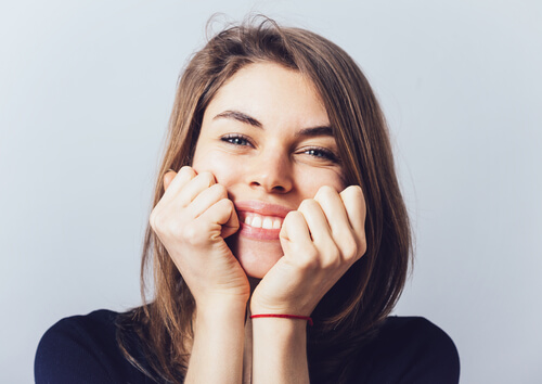 Femme souriante avec les mains sur le visage
