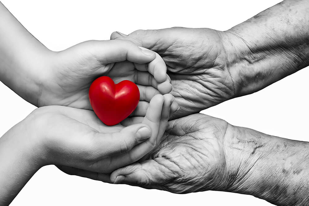 Manos diferentes edades sujetando un corazón