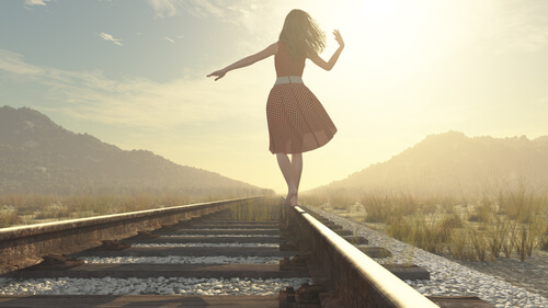 Mujer caminando por una vía mirando al futuro