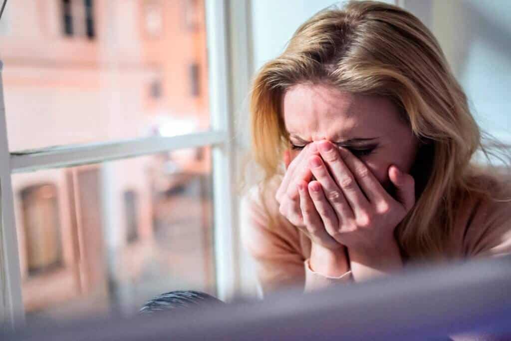 Femme qui pleure à côté de la fenêtre en manque d ocytocine