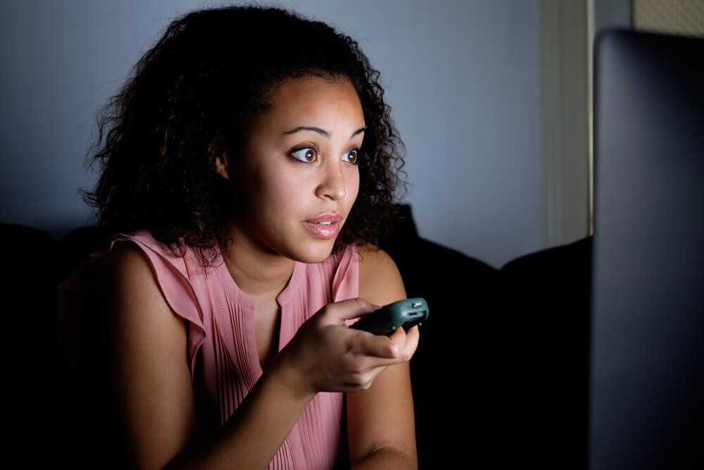 Mujer mirando la televisión con morbo