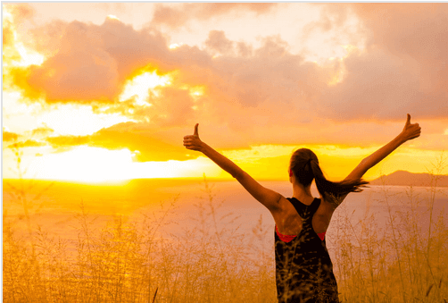 Mujer con los brazos hacia arriba al amanecer