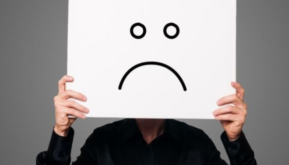 persona-sujetando-una-cartulina-blanca-enfrente-de-su-cara-con-una-cara-triste-dibujada