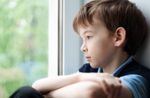 Niño triste mirando por la ventana