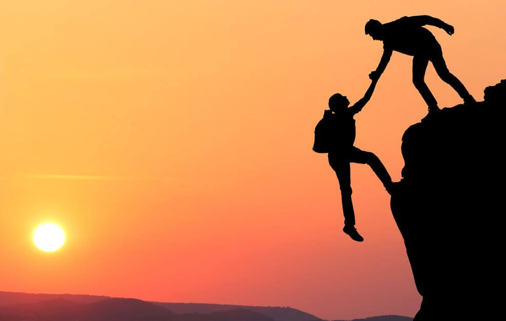 person helping someone on cliff