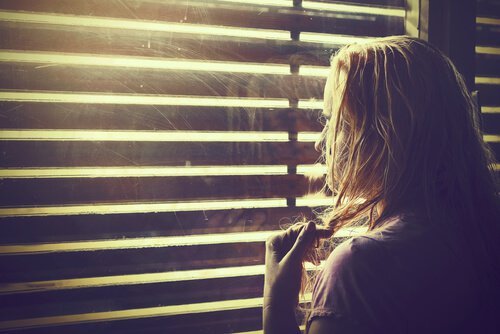 Mujer mirandopor la ventana guardando sus emociones
