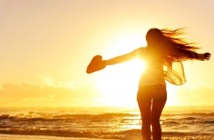 Mujer con un corazón en su mano mirando al mar