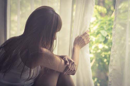 Mujer con agorafobia mirándose por la ventana