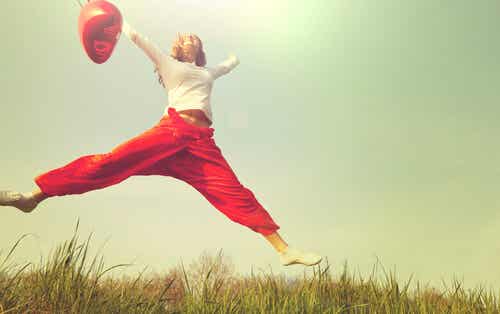 Mujer saltando con un globo rojo 