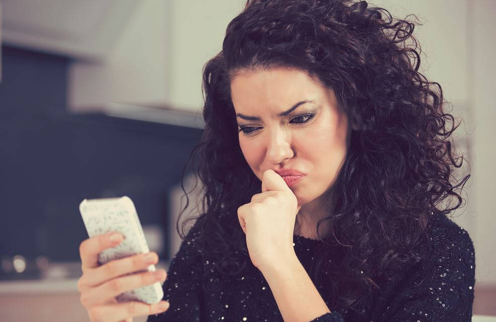 Mujer mirando el móvil con duda