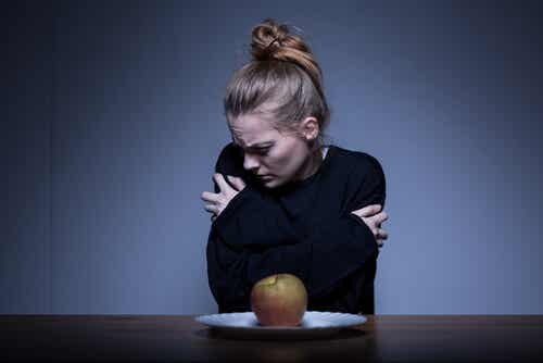 Chica con anorexia frente a una manzana