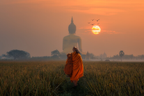 Hombre caminando con la figura de buda de espaldas en el horizonte