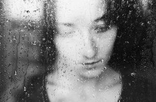 Mujer triste tras una ventana