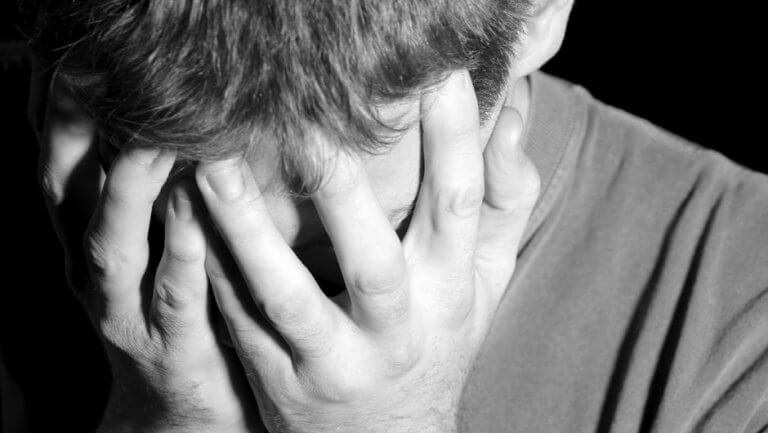 Hombre tapándose el rostro por su problema de cleptomanía