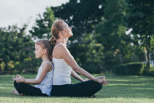 Madre e hija meditando al aire libre