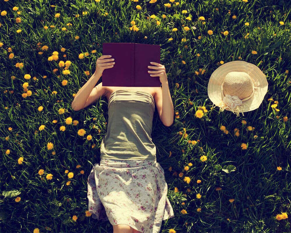 Mujer leyendo acostada sobre un jardín