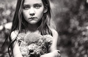 niña triste abrazada a su osito simbolizando el hijo olvidado