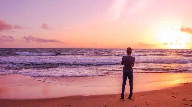 chico solitario mirando la playa al amanecer