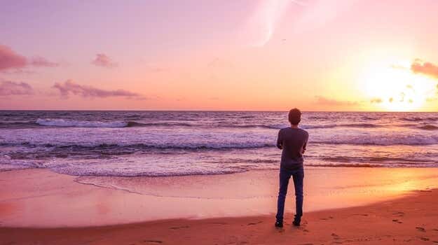 chico solitario mirando la playa al amanecer representando las frases sobre la confianza