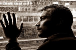 hombre inteligente con la mano sobre cristal con lluvia