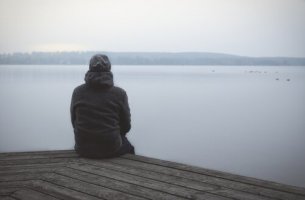 Hombre con trastorno de la personalidad esquizoide sentado mirando un lago