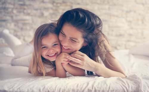 Madre con su hija encima de la cama