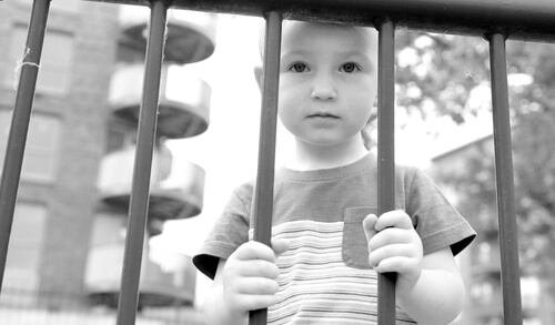 Niño detrás de unos barrotes