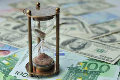 Reloj de arena sobre dinero representando las teorías de Joseph E. Stiglitz
