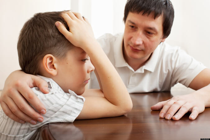 adulto poniendo mano sobre hombro de un niño