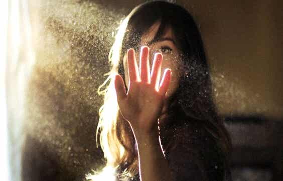 Mujer que pone la mano en haz de luz experimentando presentimientos