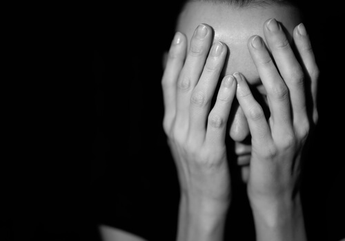 mujer triste con las manos en la cara víctima de la teoría del rumor