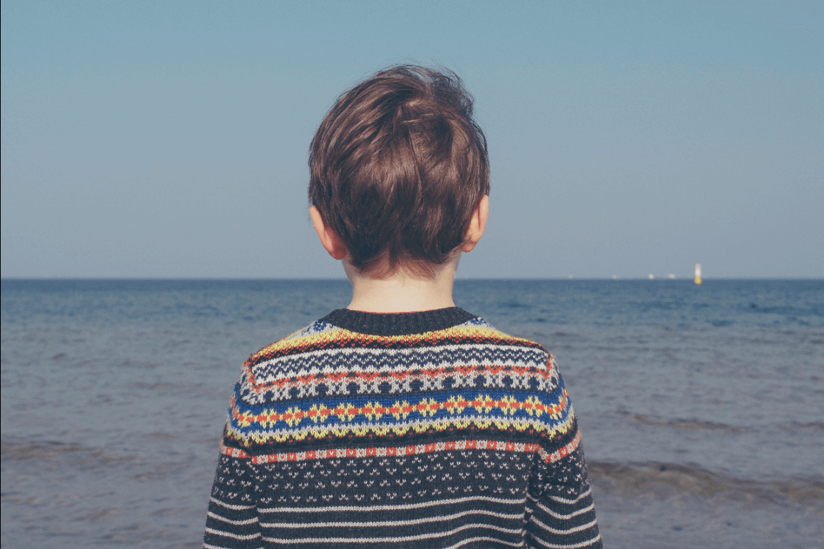 Niño de espaldas mirando al mar