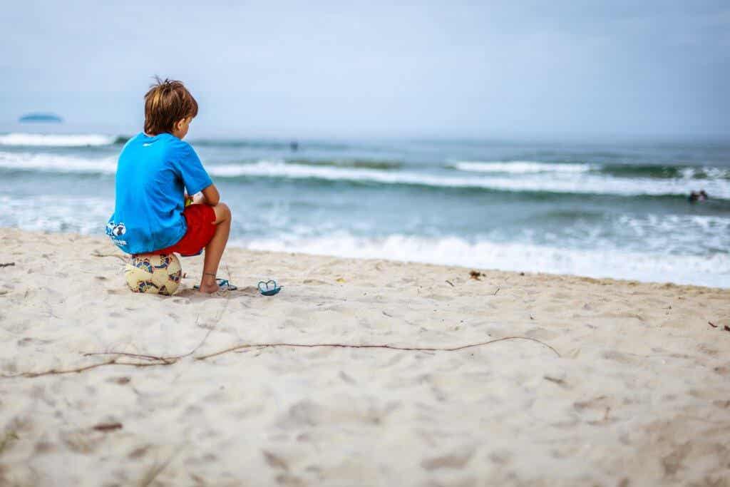 Niño mirando al mar sobre una pelota