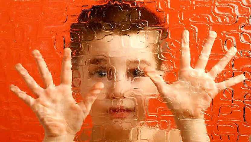 Niño con sus manos sobre un cristal por depresión enmascarada