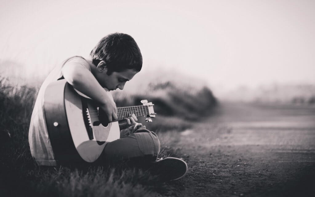 Niño triste tocando la guitarra