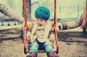 niño en el columpio con sus padres divorciados