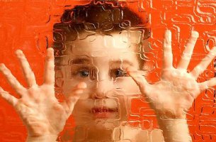 niño con esquizofrenia infantil que pone manos sobre cristal