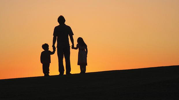 padre al amanecer con sus dos hijos de la mano