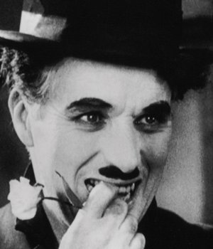 Charles Chaplin sonriendo con flor en la boca