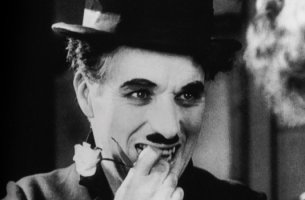 Charles Chaplin sonriendo con flor en la boca